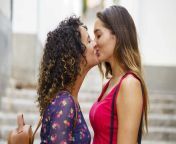 lesbian couple kissing while standing against staircase in city jsmf01784.jpg from www lesbin