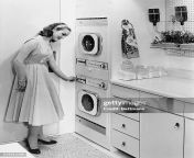 picture shows a woman turning on her washing machine in her kitchen she is wearing a dress and jpgs612x612wgik20c5jfoitqhrx3 gb4uttxupg7ui0avl8 jumtdjjr9lxo from family archive washing machine