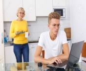 128252304 young guy sitting at kitchen with laptop while his mature mom serving him cookies.jpg from old mom and young guy