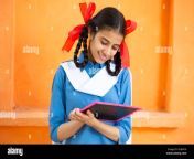 young beautiful happy indian school girl write on slate against orange background smiling braided hair female teenager kid study with black board ed 2hjn918.jpg from indian school babe 12 yars hd silpak balad xxx mp4 gym morning