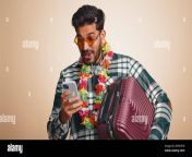 young tourist indian man with hawaiian lei in sunglasses using smartphone celebrating winning holiday resort vacation tickets pass tourism summer trip to sea handsome hindu guy on beige background 2r5rhtw.jpg from desi lei