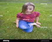 uk cornwall 9 year old girl sitting cross legged on grass lawn park axg3ab.jpg from 9yr gi
